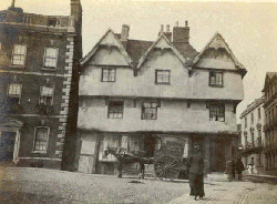 a 3 story house or inn with a horse drawn cart
